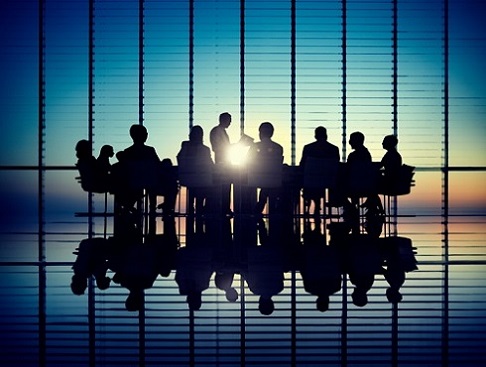 Silhouettes of business people sitting around a table at sunset.