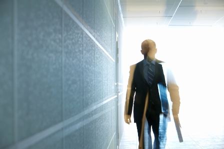 A man in a suit walking down a hallway.