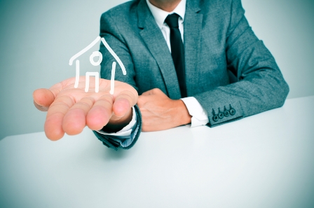 A businessman holding a hand with a house drawn on it.