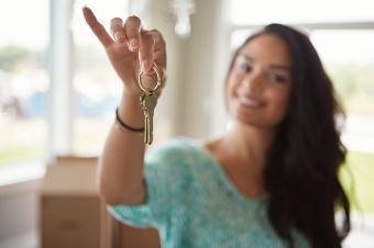 A young woman holding a key to her new home.