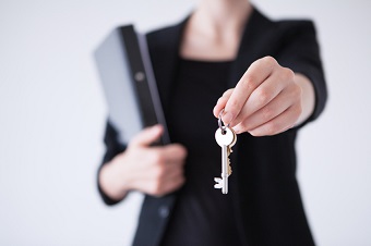 A business woman holding a key to a house.