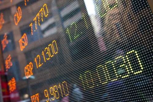 A stock market board is shown in front of a building.
