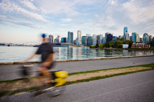 A man riding a bicycle on a path with a city in the background.