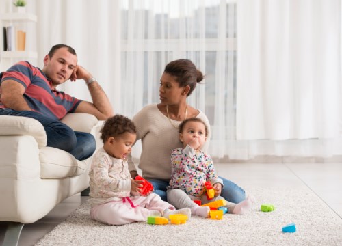 A family sitting on the floor playing with toys.