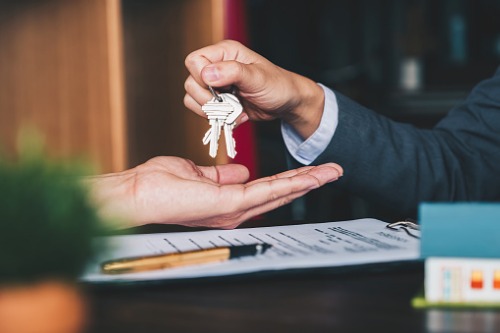 A businessman handing over keys to a house.
