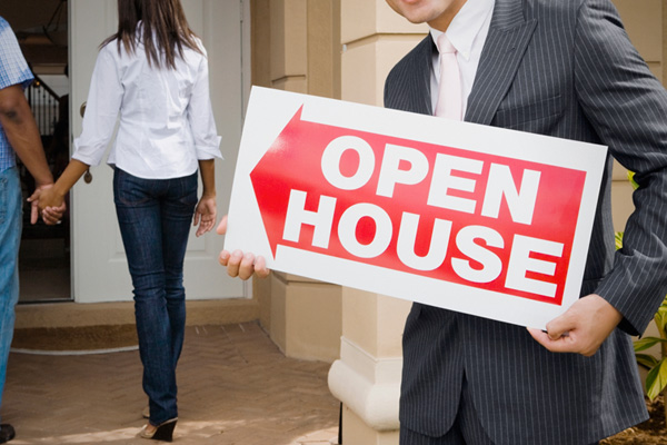 A man holding an open house sign in front of a woman.