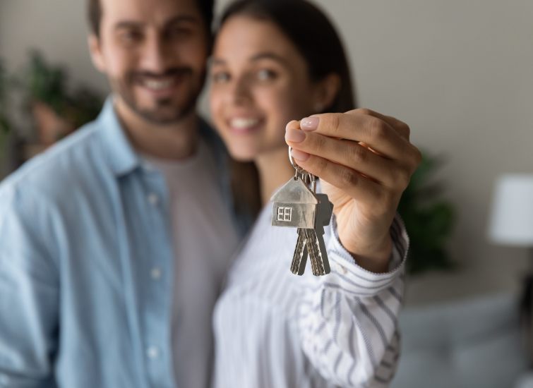 A couple excitedly holding keys to their new home, while considering mortgage rates.