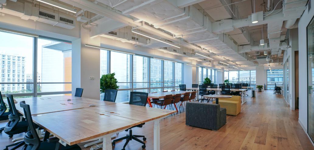 A spacious office area featuring sleek wooden tables and chairs.