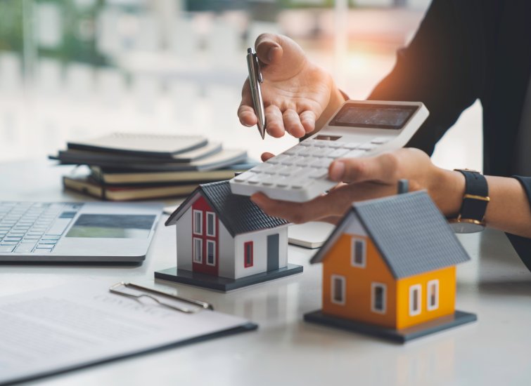 A woman holding a calculator next to a real estate model.