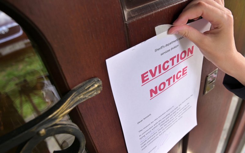 A person holding an eviction notice on a door, indicating impending eviction.