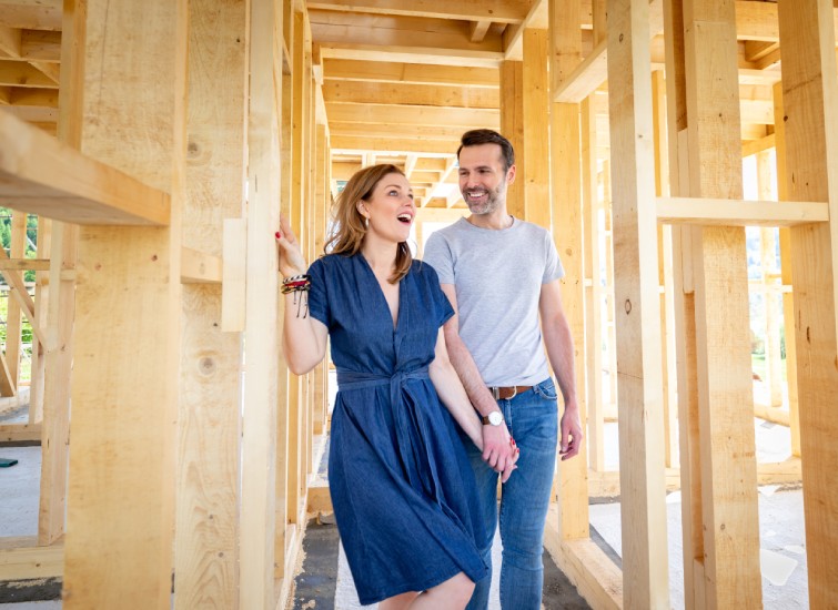 A young couple standing in the framing of a new home.