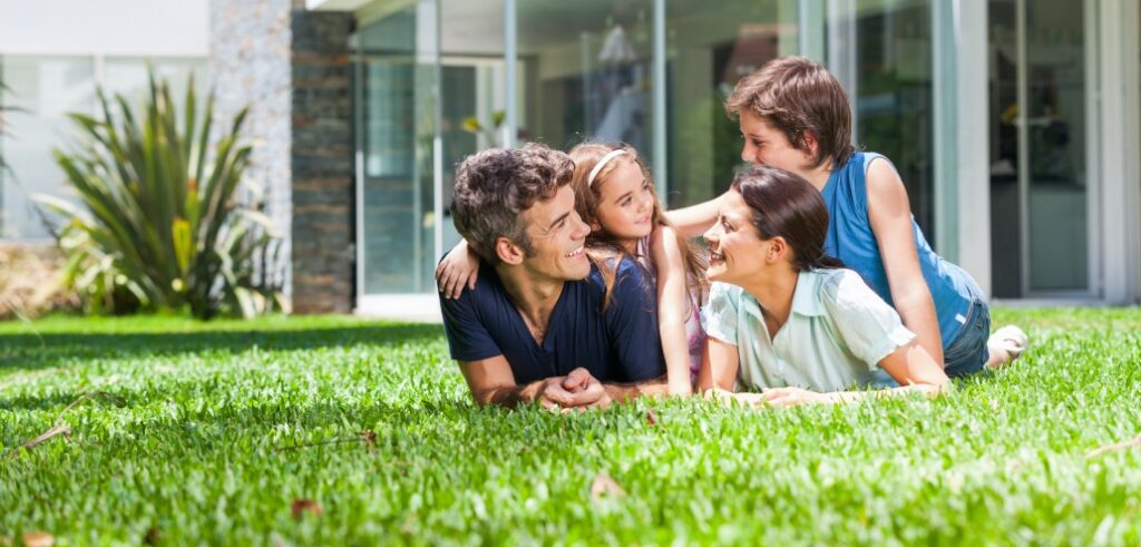 A family relaxing on the grass in front of their home.