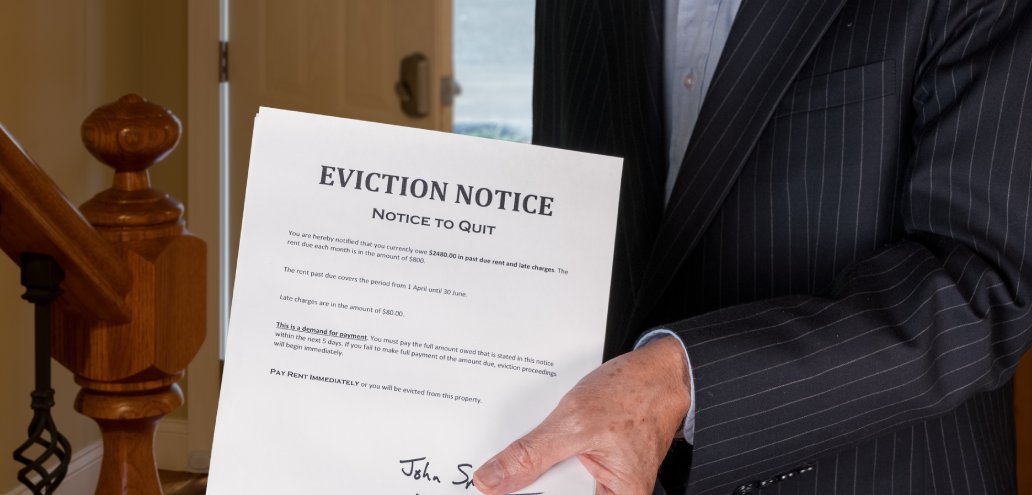 A man in a suit holding an eviction notice, signaling impending eviction for a tenant.