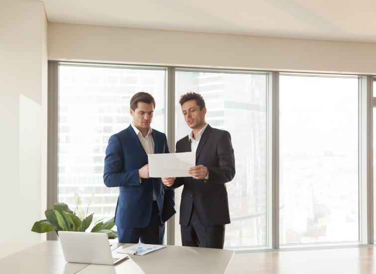 Two businessmen examining a property document in an office.