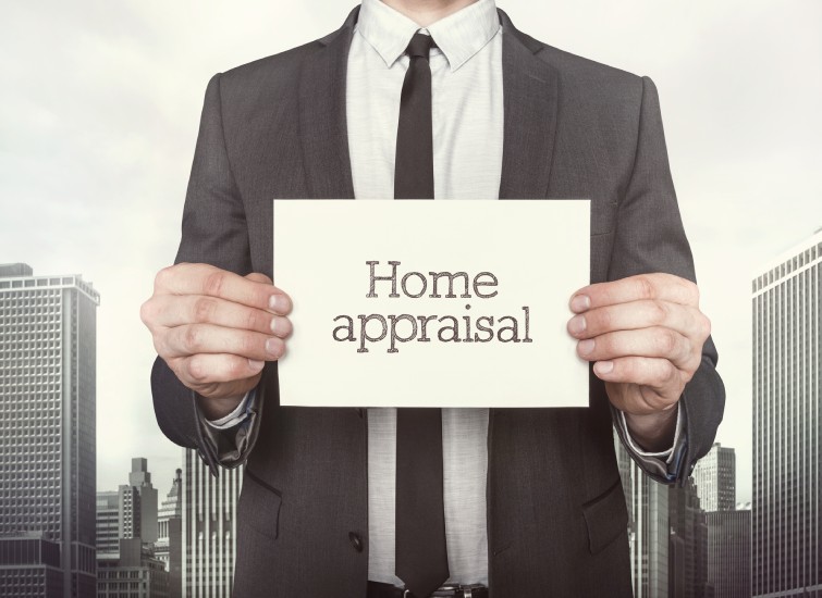 A businessman holding up a sign that says home appraisal.