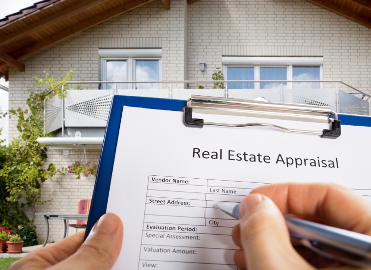 A person holding a real estate appraisal clipboard in front of a house.