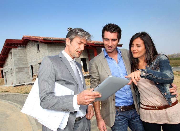real estate agent showing house under construction to couple