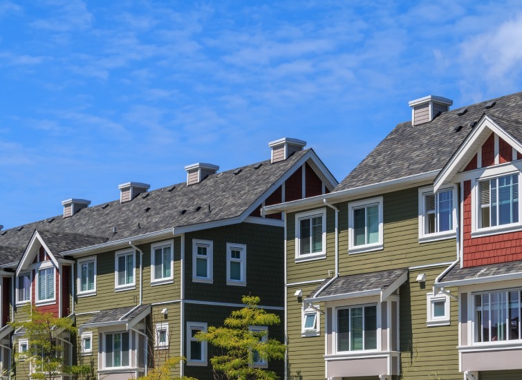 A row of houses with green siding and blue sky.