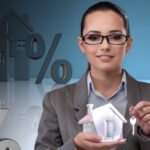 A woman holding up a house model and dollar signs.