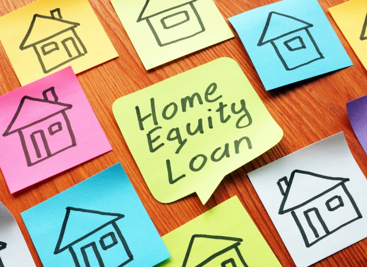 Sticky notes with house drawings and the words "home equity loan" on a wooden surface.