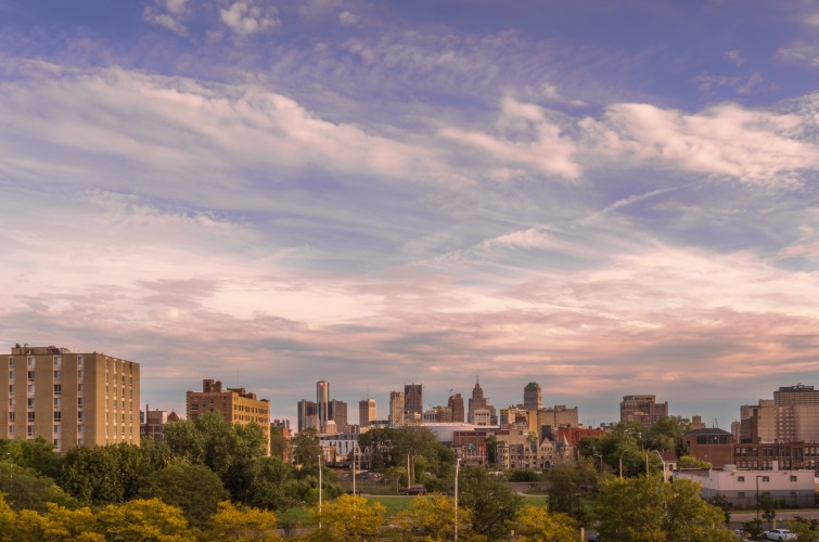 A city skyline at dusk with pink-tinged clouds in the sky.