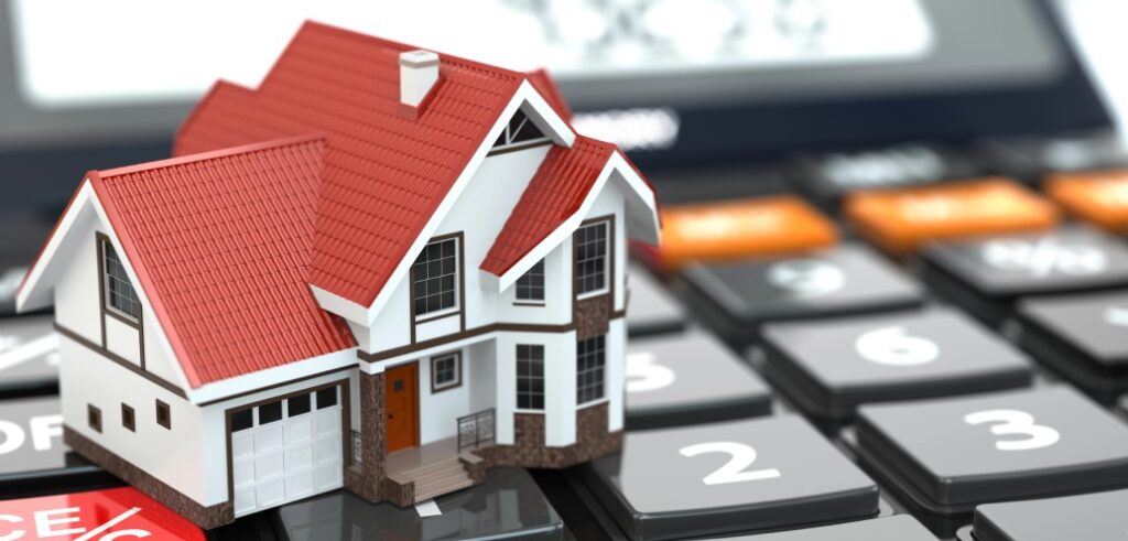 Miniature house model placed on a calculator, symbolizing home finance or mortgage calculations.