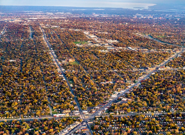 Aerial view of a sprawling suburban area with autumn foliage and intersecting roadways.