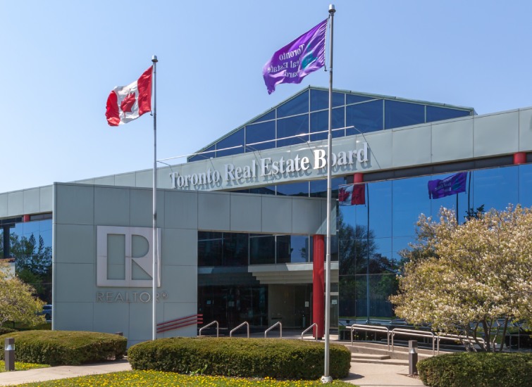 The Toronto real estate board building, now part of the National Association of REALTORS, with Canadian flags and purple banners on a sunny day.