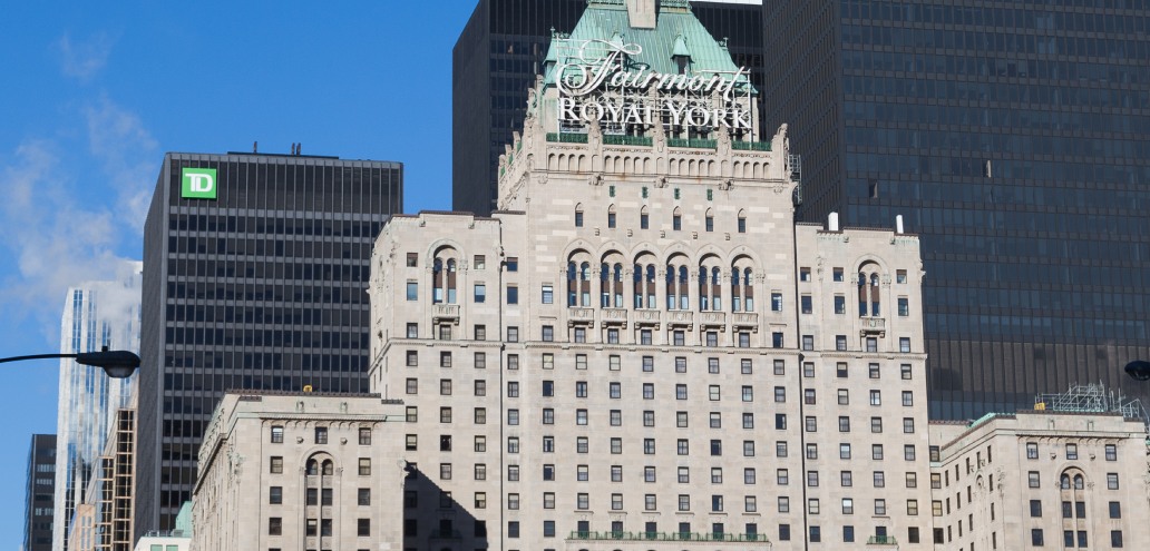 Historic fairmont royal york hotel amidst modern skyscrapers in a downtown cityscape.