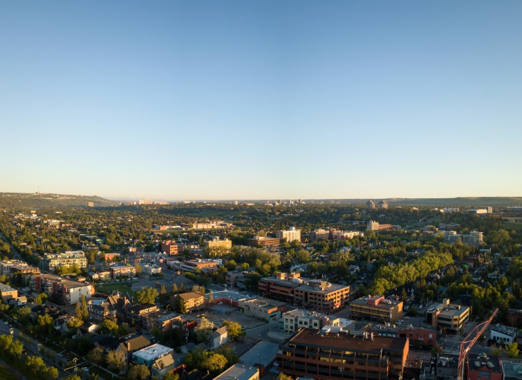 Aerial view of a city at sunset, showcasing residential and commercial real estate investments spread across a lush, tree-filled landscape.